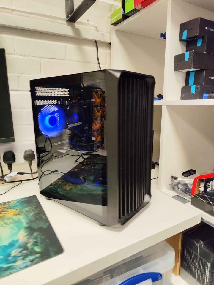 Custom PC build on the shop workbench with stocked shelves